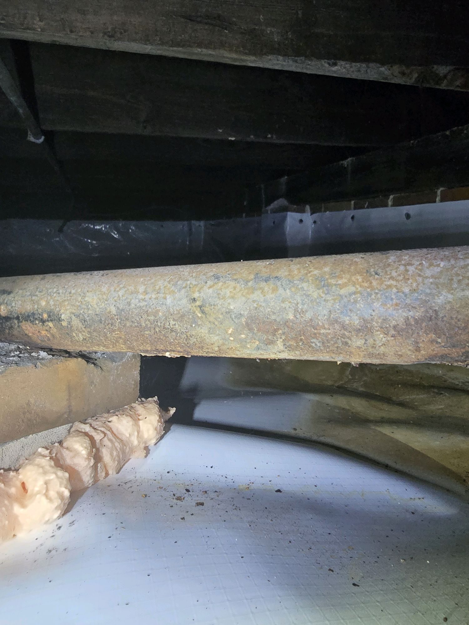 Cast iron drain pipe in a crawlspace showing rust blistering, inspected during a home inspection