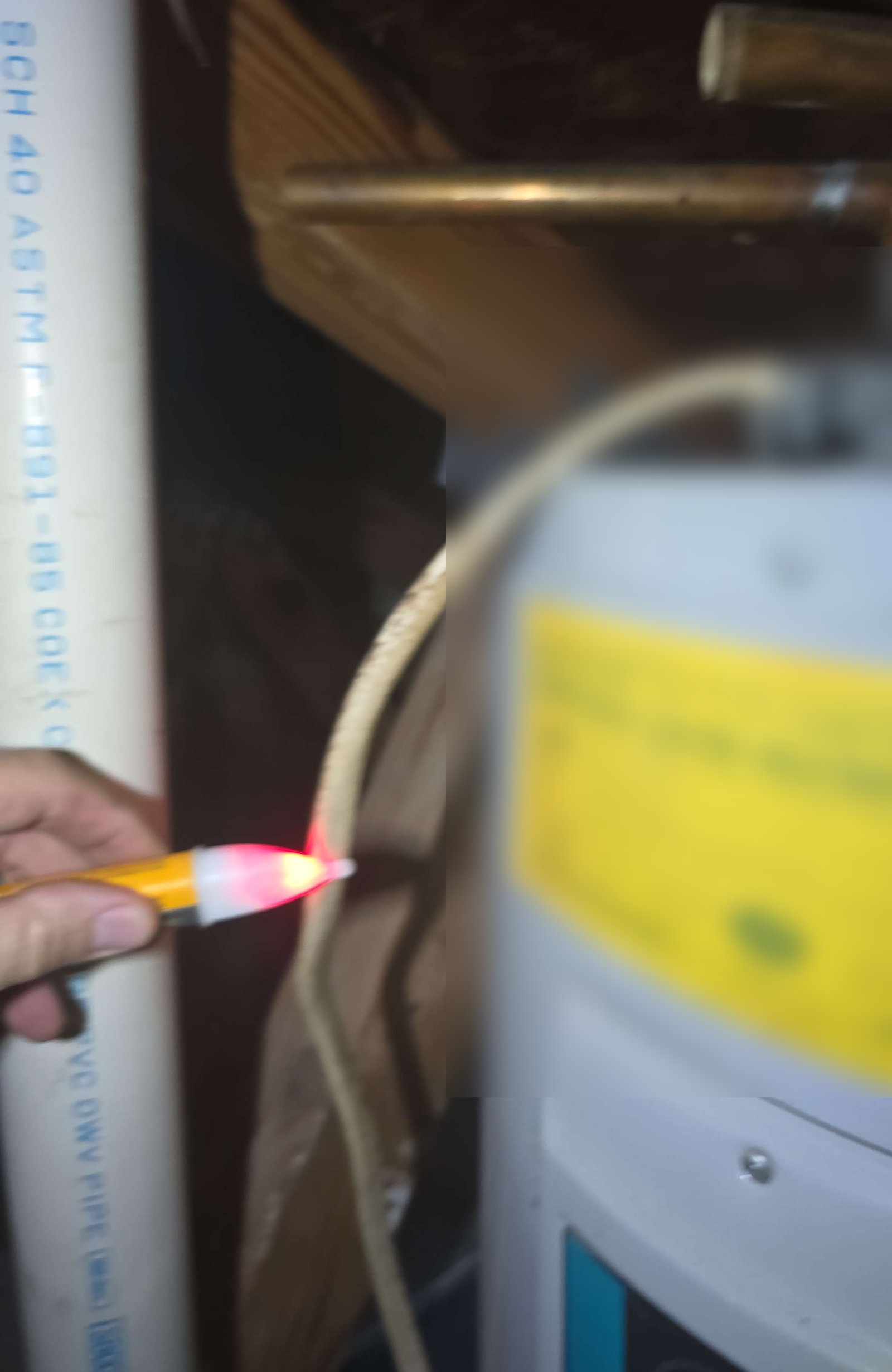Voltage tester showing live wiring at a retired attic water heater